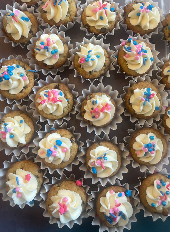 Colorful cookies topped with creamy frosting and vibrant sprinkles arranged on a decorative plate.